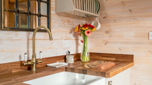 Une cuisine avec un plan de travail en bois, un évier blanc et un vase de fleurs.