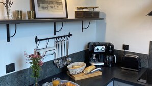A modern kitchen with a black countertop, white cabinets, a coffee maker, toaster, and a framed picture on the wall. - Large 4* gîte: sleeps 12, 6 bedrooms, 4 bathrooms, games room, garden (Laon)
