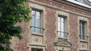 A two-story brick building with a central entrance, large windows, and a decorative facade. - Large 4* gîte: sleeps 12, 6 bedrooms, 4 bathrooms, games room, garden (Laon)