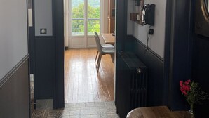 A hallway with a patterned floor, a wooden bench, a radiator, and a door leading to a balcony with a view of greenery. - Large 4* gîte: sleeps 12, 6 bedrooms, 4 bathrooms, games room, garden (Laon)