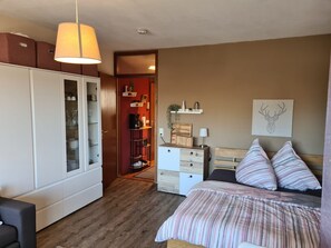 Une chambre à coucher comprenant un lit, une armoire, une table de chevet, une lampe et une décoration murale représentant une tête de cerf.