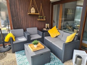 A seating area with wicker furniture, a small table with a plant, and hanging lanterns.