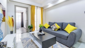 A modern living room with a grey sofa, yellow cushions, a coffee table, and a plant. - Yaya Suites (Nairobi)