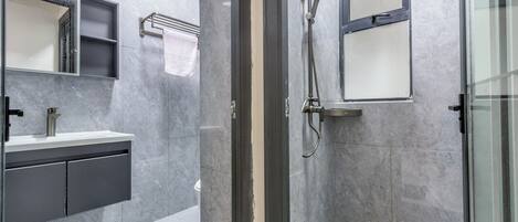 A modern bathroom with a glass-enclosed shower, a sink with a mirror, and a towel rack.