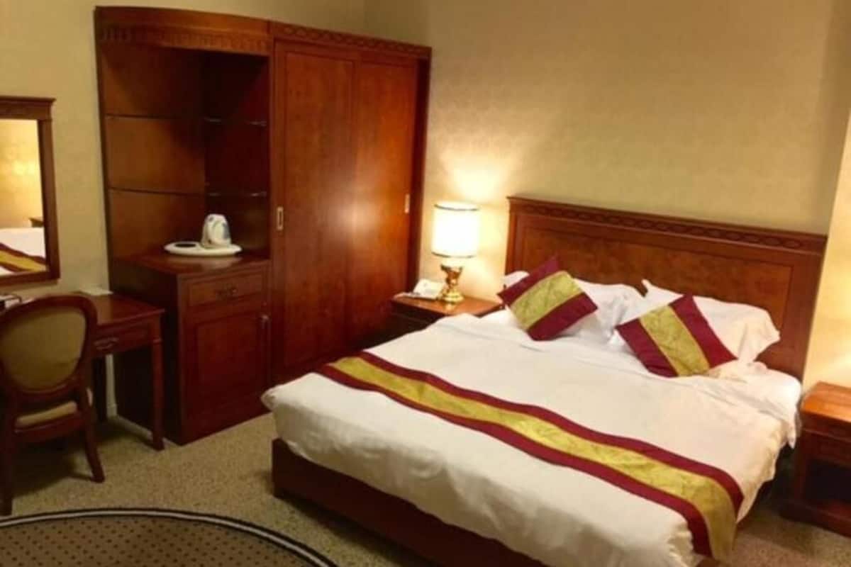 Une chambre d’hôtel avec un grand lit, une armoire en bois, un bureau et une chaise.