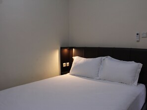 A hotel room with a bed, a nightstand, and a wall-mounted light. - Arisa Villa by AGATA (Tembuku)