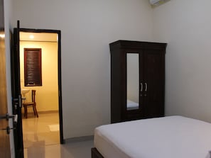 Ein Schlafzimmer mit einem Bett, einem Kleiderschrank, einer Tür zu einem Badezimmer und einem Fenster mit Jalousien.