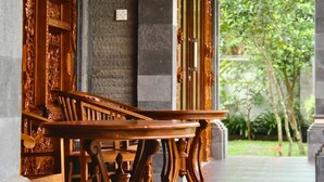 Una mesa de madera con patas decorativas en un espacio cubierto con paredes de piedra y vistas al verdor exterior.