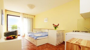 Une pièce de taille modeste comprenant un lit, une petite kitchenette et un coin repas.