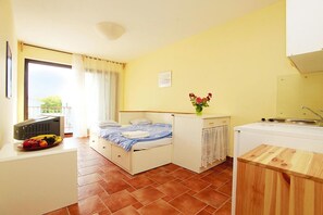 Een kleine kamer met een bed, een kitchenette en een eethoek.