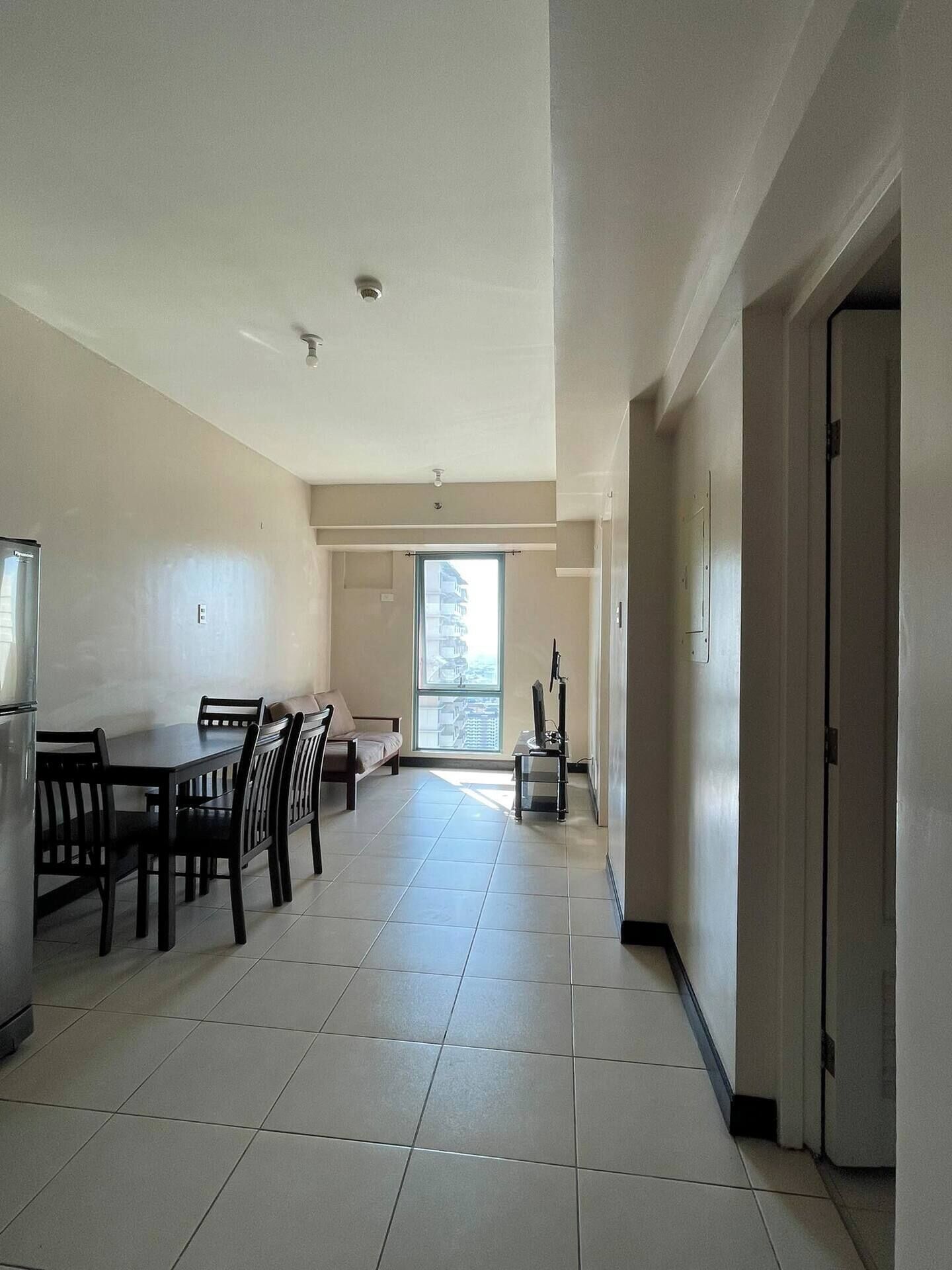 A spacious kitchen with a dining area, a refrigerator, and a window with a view of buildings.