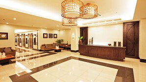 Um hall amplo com balcão de recepção, área de estar e um lustre moderno.
