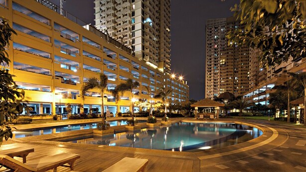 Um hotel com vários edifícios altos, piscina e áreas de estar ao ar livre.