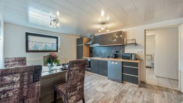 A modern kitchen with a built-in dishwasher, a microwave, and a coffee maker. There is a dining area with a table and chairs.