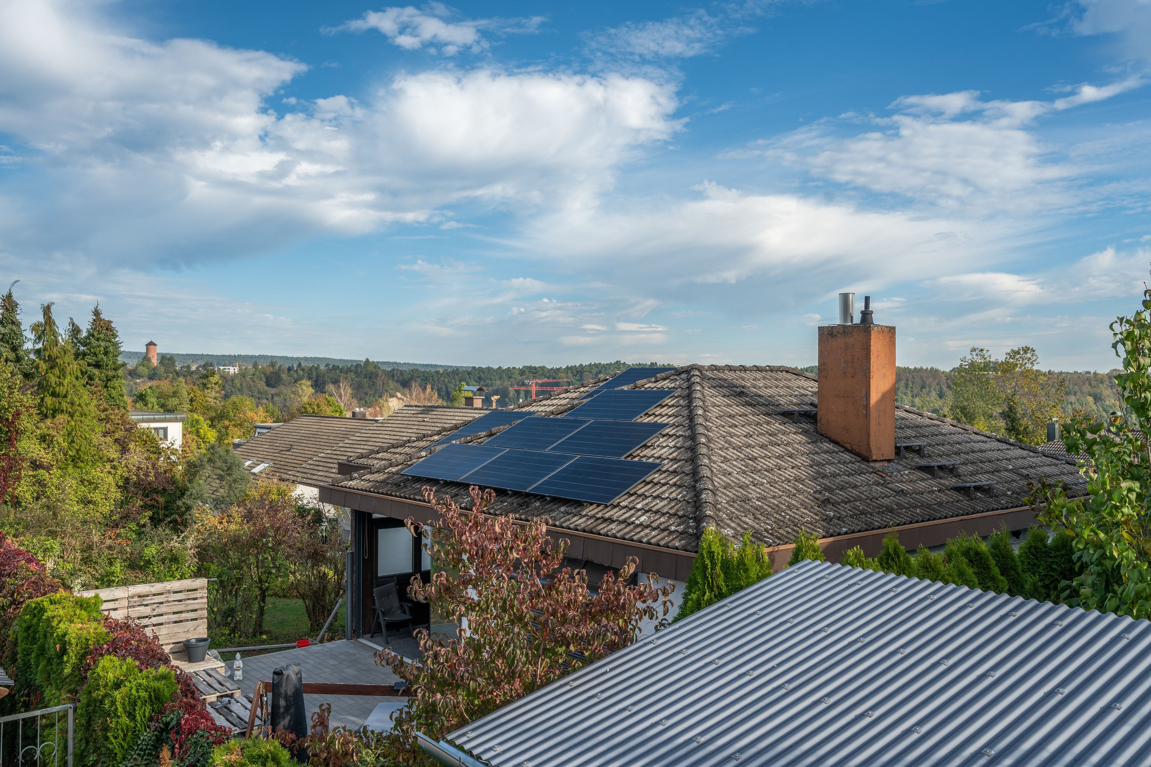 A residential building with a sloped roof, solar panels, and a chimney.