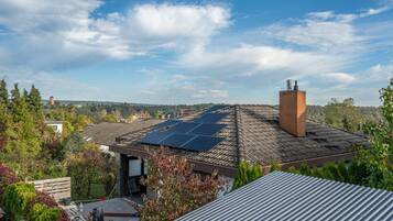 A residential building with a sloped roof, solar panels, and a chimney.