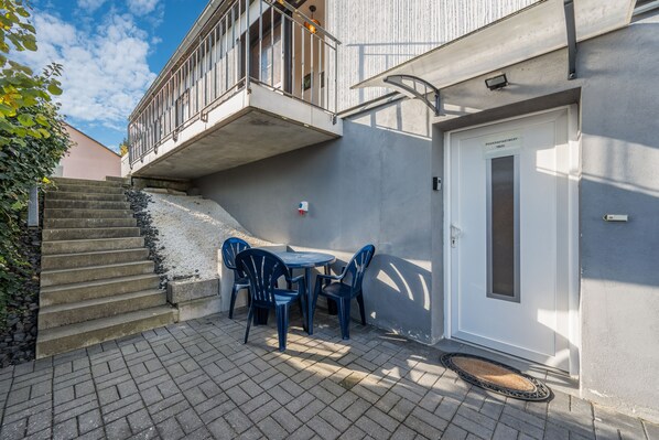 A building with a balcony, a door labeled 'Feriendapartment,' and a small outdoor seating area with chairs and a table.