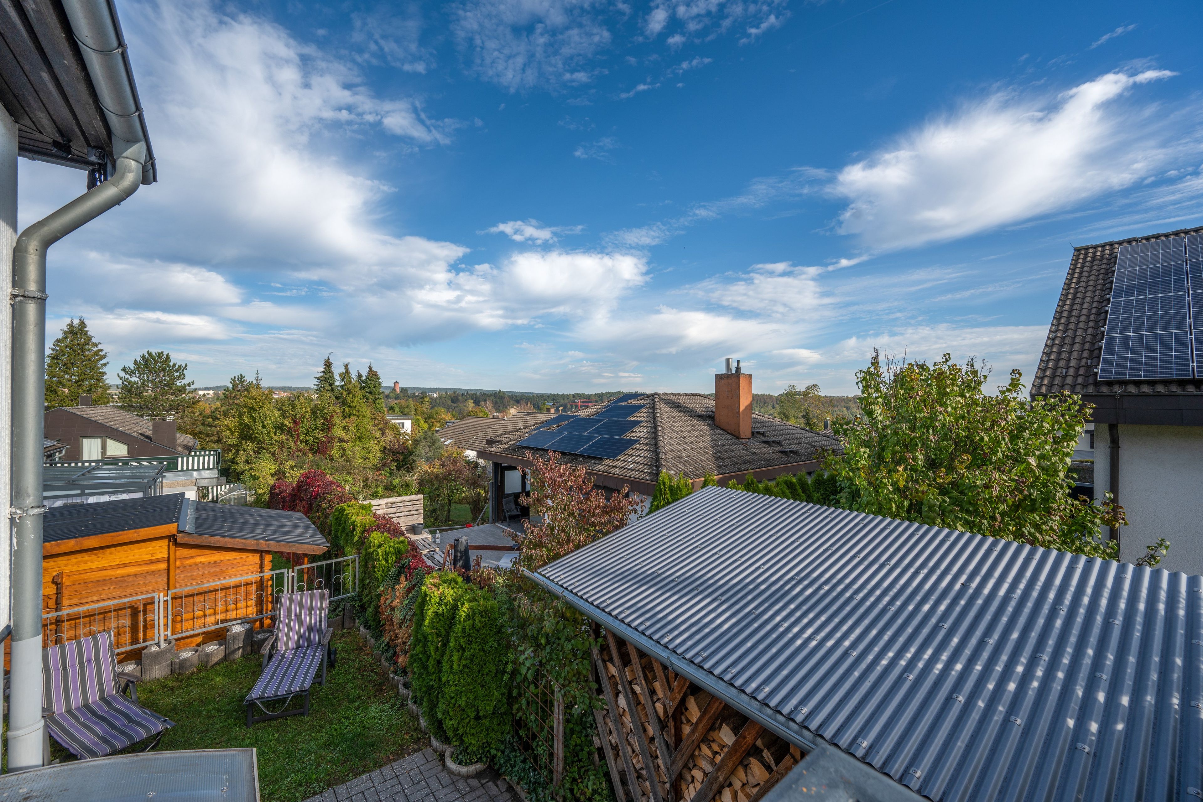 A residential area with a view of a house with solar panels, a wooden deck, and a garden.