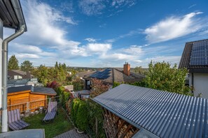 Un quartier résidentiel offrant une vue sur une maison équipée de panneaux solaires, dotée d’une terrasse en bois et d’un jardin.
