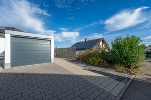 Une propriété résidentielle comprenant un garage, une allée pavée et une maison équipée de panneaux solaires.