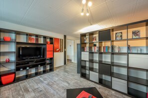 Un salon moderne doté d’un téléviseur à écran plat, d’étagères intégrées et d’une cheminée.