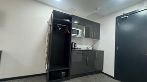 Une petite pièce comprenant un coin cuisine, une armoire et une porte.