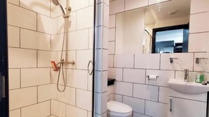 Une salle de bain moderne avec une douche à parois de verre, des toilettes et un lavabo avec un miroir au-dessus.