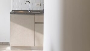 Uma cozinha moderna com armários brancos, painel de azulejos branco e uma pia de aço inoxidável.