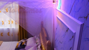 A bedroom with a bed, pillows, a canopy, and a wall with a crack pattern. - Flo Homes White House Apartments, Thome Nairobi (Nairobi)