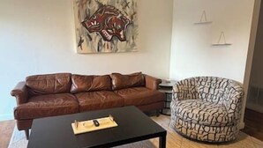 A living room with a brown leather sofa, a black coffee table, and a patterned armchair.