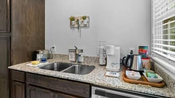 A kitchen with granite countertops, a double sink, and wooden cabinets.