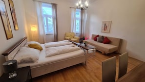 A modern bedroom with a bed, bedside table, lamp, and a sofa with cushions. - Spacious 2BR Apt Long Stay in Vienna (Vienna)