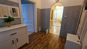 A room with a wooden floor, a white dresser, a plant on the dresser, and a door leading to another room. - Spacious 2BR Apt Long Stay in Vienna (Vienna)