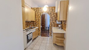 Une cuisine de taille réduite, équipée d’une cuisinière à gaz, d’un évier et de meubles de rangement en bois.