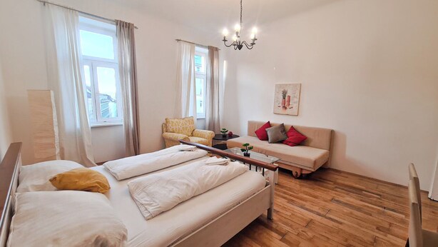 Une chambre à coucher comprenant un lit, un canapé, une chaise, une table de chevet et une fenêtre.