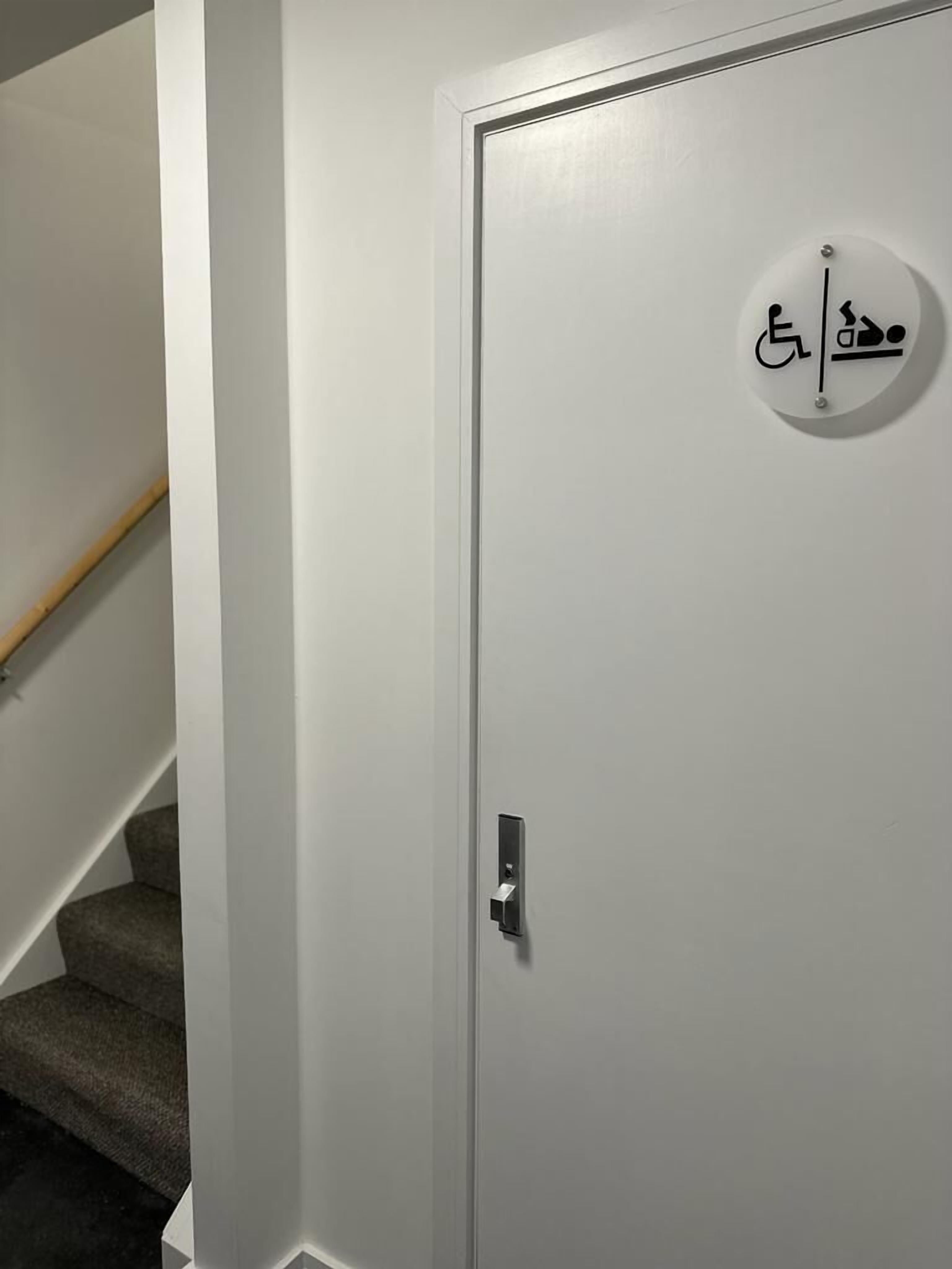A white door with a wheelchair accessibility symbol and a doormat.