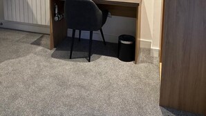 A small, modern room with a wooden desk, a black chair, a flat-screen TV mounted on the wall, a kettle, and a coffee cup on the desk. - Fox and Hounds Inn (Carmarthen)