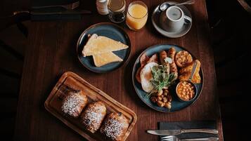 Une table de petit-déjeuner avec des toasts, des saucisses, des haricots et une boisson.