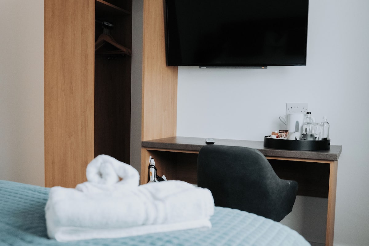 A hotel room with a bed, a desk, a TV, and a wardrobe.