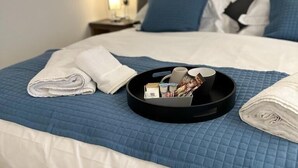 A neatly made bed with a blue quilt, a tray with toiletries, and a folded towel. - Fox and Hounds Inn (Carmarthen)