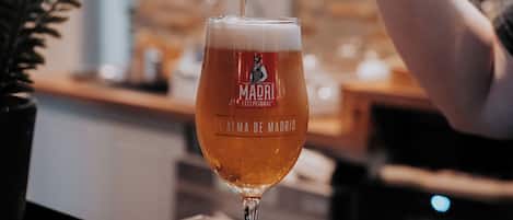 A glass of beer being poured from a tap labeled "MADRI."