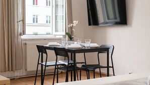 A dining area with a table set for four, a potted plant, and a TV mounted on the wall. - Bright 2BR Apt Perfect Long Stay (Vienna)