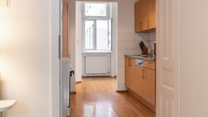 A narrow kitchen with wooden cabinets, a white radiator, and a window with a view. - Bright 2BR Apt Perfect Long Stay (Vienna)
