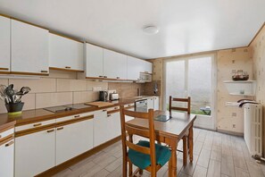 Una cucina con mobili bianchi, un tavolo da pranzo in legno e vista attraverso una porta vetrata.