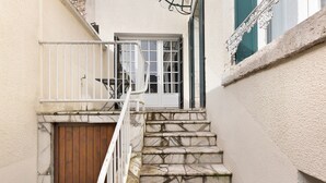 A staircase with stone steps and a wooden door, leading to a white door with a window. - Gîte Du Centre with Private Terrace and Wi-Fi (Romorantin-Lanthenay)