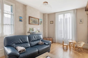Un salon avec un canapé en cuir, une table en bois et un fauteuil en osier.