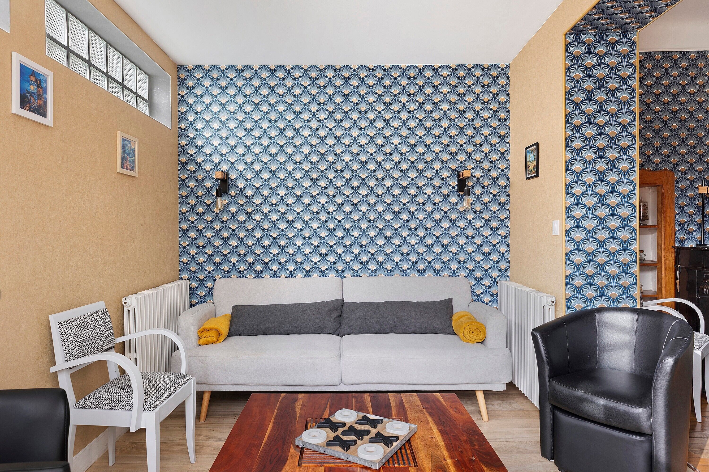 A living room with a sofa, chairs, a coffee table, and patterned wallpaper.
