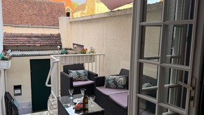 A patio with outdoor furniture, a table with glasses and a bottle, and a view of buildings in the background. - Gîte Du Centre with Private Terrace and Wi-Fi (Romorantin-Lanthenay)