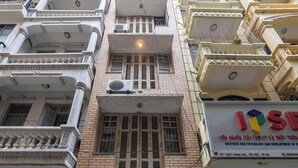 A multi-story building with a green gate, a sign for the Institute for Psychology and Development of Children, and multiple air conditioning units. - Homestay PW Hoang Sam (Hanoi)