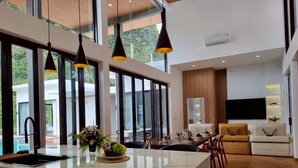A modern kitchen with a large island, black pendant lights, and a view of the outdoors. - Red Cheek Mountain Villa  (Krabi)